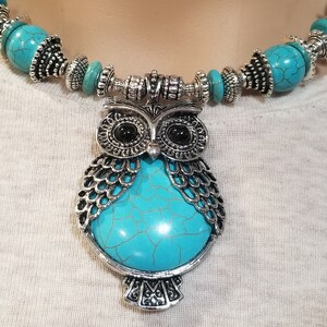 May include: A turquoise and silver owl pendant necklace. The owl is made of metal with a turquoise stone in the center. The necklace is made of turquoise beads and silver spacers.