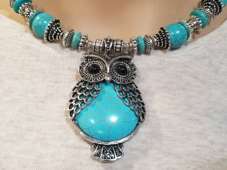 May include: A turquoise and silver owl pendant necklace. The owl is made of metal with a turquoise stone in the center. The necklace is made of turquoise beads and silver spacers.