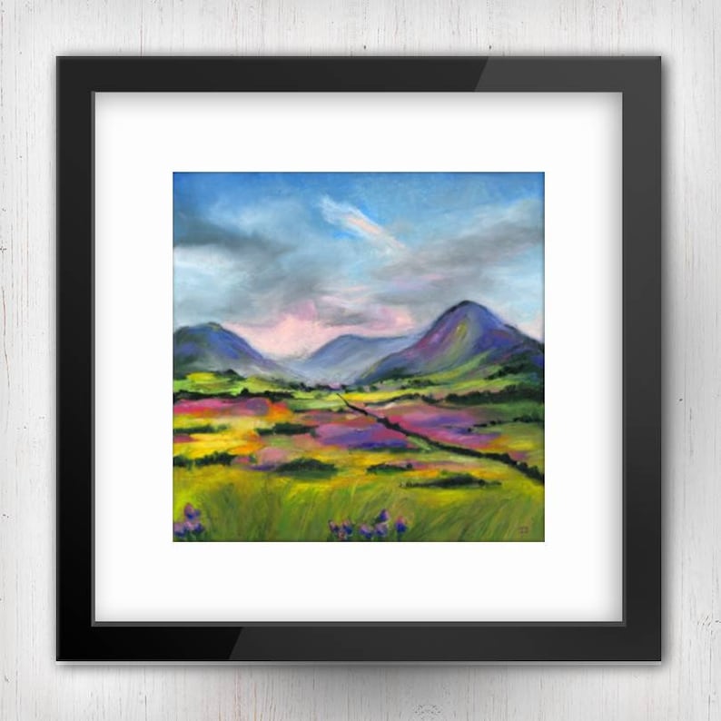 May include: An original landscape painting in a black frame. The artwork depicts a colorful field of flowers in shades of yellow, pink, and purple, with rolling green hills and mountains in the background. The sky is a mix of blue and gray.