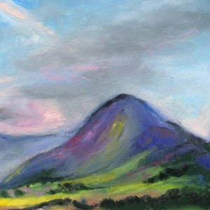 May include: An original pastel painting of a mountain landscape. The mountain is painted in shades of purple and blue, with green and yellow accents on the hillside. The sky is a mix of blue, gray, and pink hues, creating a soft, atmospheric effect.