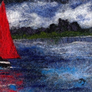 May include: A red sailboat with a white sail on a blue body of water with a dark green shoreline and a dark silhouette of a city in the background. The sky is a dark blue with white clouds.