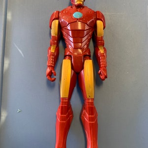 K&ouml;nnte beinhalten: Eine rote und goldene Iron Man Actionfigur mit einer blauen Gesichtsmaske. Die Figur steht auf einer blauen Oberfl&auml;che.