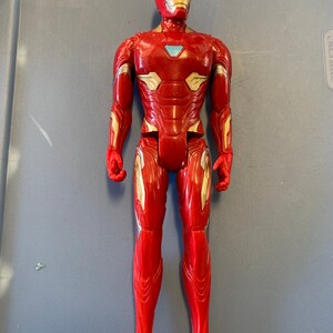 May include: A red and gold action figure of Iron Man, a superhero from the Marvel universe. The figure is posed standing with its arms at its sides. The figure has a detailed design with a red and gold suit and a blue and silver face mask.