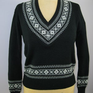 May include: Black sweater with a white geometric pattern around the neckline and hem.