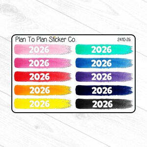 May include: A sticker sheet featuring the text "2026" in white, displayed on colorful brushstroke backgrounds. The colors include pink, magenta, red, orange, yellow, teal, blue, purple, dark blue, and black. The sticker sheet has the text "Plan To Plan Sticker Co." and "2410-26".