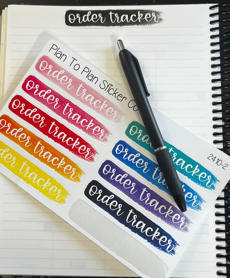 K&ouml;nnte beinhalten: Ein Blatt mit bunten Aufklebern f&uuml;r die Auftragsverfolgung mit einem schwarzen Stift darauf. Die Aufkleber sind in einem Regenbogen von Farben gehalten und haben den Text "order tracker" in Wei&szlig; auf jedem Aufkleber. Der Text "Plan To Plan Sticker Co." ist oben auf dem Blatt sichtbar.
