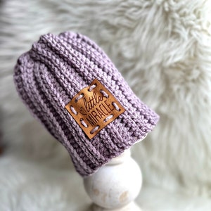 May include: A purple crocheted baby hat with a brown leather patch that says "little miracle".