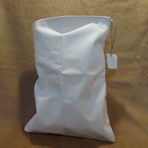 May include: A white cotton drawstring bag with a small white tag attached to the drawstring.