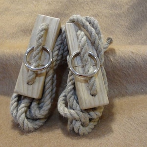May include: Two wooden rope toggles with metal rings. The toggles are made of natural wood and have a rope wrapped around them. The rope is a natural brown color.