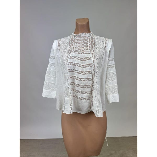 Blusa de algodón blanca estilo eduardiano de la década de 1910 con corte de encaje, peplum, botones, lazo en la cintura, festones, ojales, estampado floral, rayas y cuadrados.