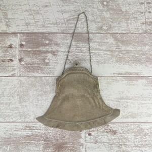 May include: A silver mesh purse with a chain strap. The purse is closed and has a decorative clasp.