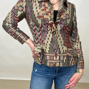 May include: A patterned jacket with a button closure and a collar. The jacket is made of a woven fabric with a geometric design in shades of brown, green, purple, and red.