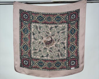 Könnte beinhalten: Ein rosa Seidentuch mit einem Paisley-Muster und einem Rand aus geometrischen Mustern in Rot-, Blau- und Goldtönen.