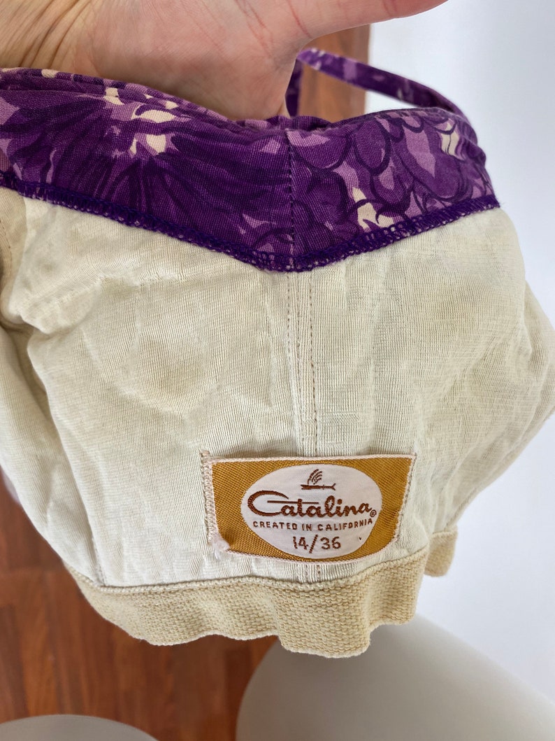 以下が含まれることがあります： 花柄のベージュとパープルの水着の上半身。トップには「Catalina Created in California 14/36」と書かれたラベルが付いています。