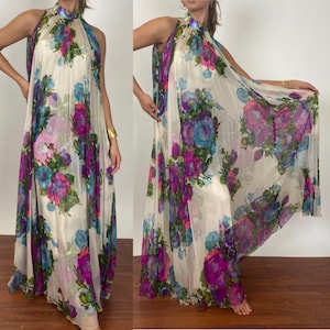 Puede incluir: Un vestido largo y fluido de color blanco con cuello alto y estampado floral en tonos morados, azules y verdes.