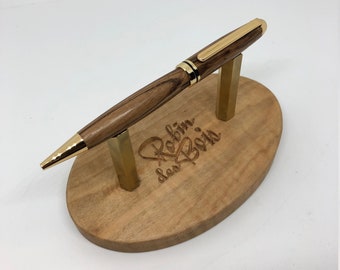 May include: A wooden pen with a gold trim and a heart design engraved on the stand. The stand is made of wood and has the words "Robin des Bois" engraved on it.