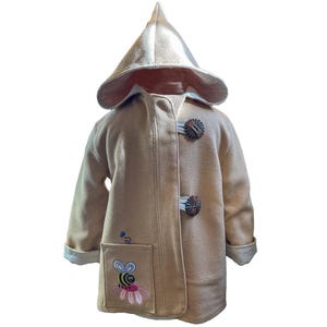 May include: A beige hooded coat with a bee embroidered on the pocket. The coat has wooden toggle closures and a white lining.