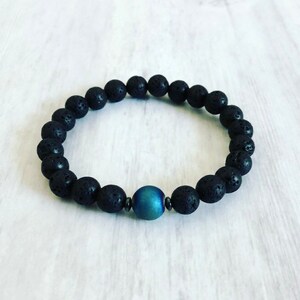 May include: A black lava rock beaded bracelet with a single blue agate bead.