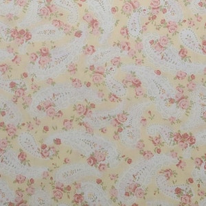 May include: A yellow fabric with a white paisley pattern and pink floral accents.