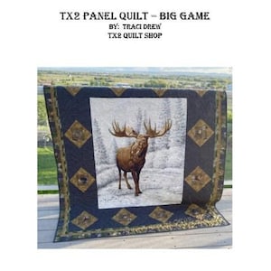 May include: A large panel quilt featuring a detailed image of a moose in a snowy forest scene. The quilt has a dark blue border with gold diamond accents and a patterned edge. The text "TX2 PANEL QUILT = BIG GAME" is at the top.