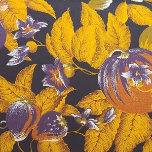 May include: A dark purple fabric with a repeating pattern of yellow leaves, purple flowers, and orange pumpkins. The fabric has a vintage feel and would be perfect for a fall-themed project.