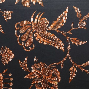 May include: A black fabric with a repeating pattern of orange and white floral designs. The fabric has a traditional batik style.