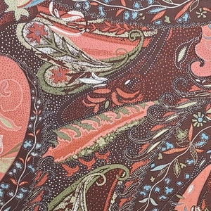 May include: A brown fabric with a paisley pattern in shades of pink, green, and blue. The fabric has a subtle shimmer and a textured surface.