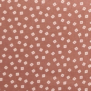 May include: A brown fabric with a repeating pattern of small white squares. The squares are arranged in a diagonal pattern.