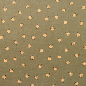 May include: Close-up of a fabric with a repeating pattern of small, light orange sunburst shapes on a muted green background. The sunbursts have a circular center with radiating lines.