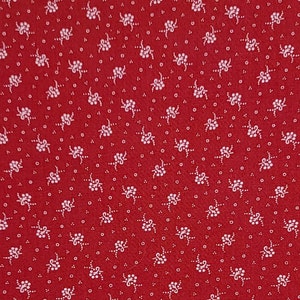 May include: Red fabric with a white floral pattern. The pattern is a repeating design of small white flowers with a white stem.