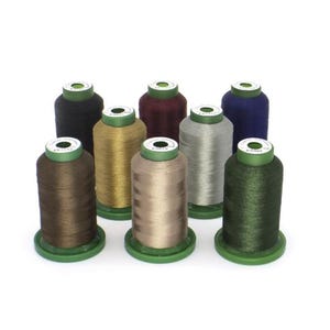 May include: A collection of eight spools of thread in various colors, including black, gold, brown, silver, and navy blue. Each spool is cylindrical with a green base and top. The threads appear to be smooth and shiny.