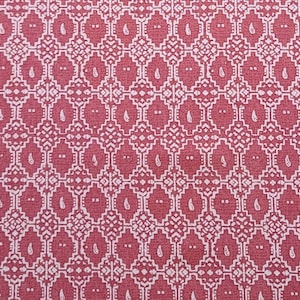May include: A red fabric with a white geometric pattern. The pattern is made up of small squares and diamonds, with a paisley-like design in the center of each square.