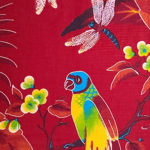 May include: A parrot with blue, green, and yellow feathers perches on a branch with red, brown, and green leaves. The background is a solid red color with a white dragonfly.