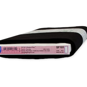 May include: A roll of black fabric with a white label. The label reads "SF101 Shape-Flex" and includes details about the fabric's composition and care instructions. The fabric is 26 inches wide and made in the USA.