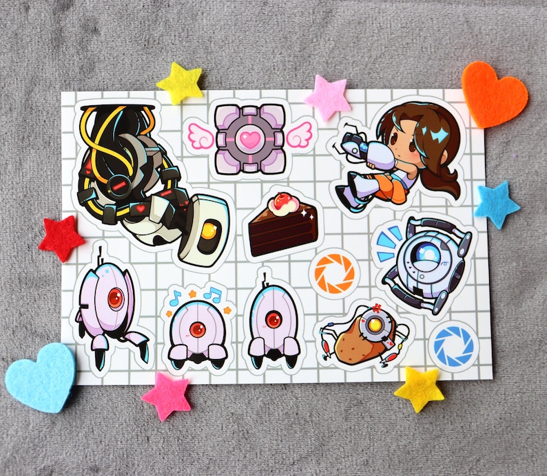 Puede incluir: Un conjunto de 11 pegatinas con personajes y objetos del videojuego Portal. Las pegatinas est&aacute;n impresas en papel blanco con un patr&oacute;n de cuadr&iacute;cula. Las pegatinas incluyen una pistola portal, un cubo compa&ntilde;ero, un pastel, una torreta y una patata.