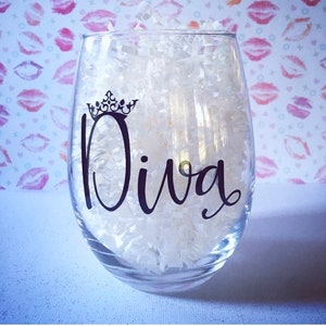 May include: A clear glass wine glass with the word "Diva" written in black cursive lettering with a crown above the word.