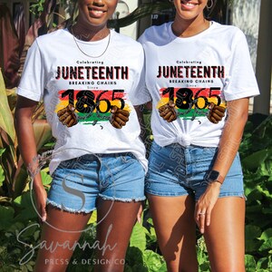 May include: Two white t-shirts with the text "Celebrating Juneteenth Breaking Chains Since 1865" in black and red lettering. The number 1865 is surrounded by a red, yellow, green, and black striped design with a chain and two hands breaking free.
