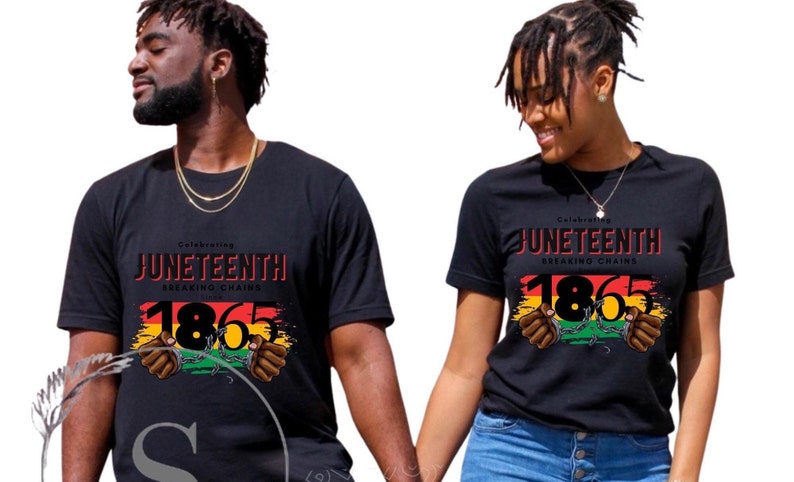 May include: Two people wearing black t-shirts with a graphic design celebrating Juneteenth. The design features the year 1865, a red, yellow, and green flag, and two hands breaking chains.