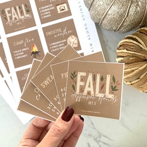 Può includere: Un set di carte marroni con testo bianco e illustrazioni. Le carte presentano diverse miscele di diffusori per l'autunno, tra cui "Fuoco da campo", "Tempo da maglione" e "Miscele di diffusori autunnali Set 2".