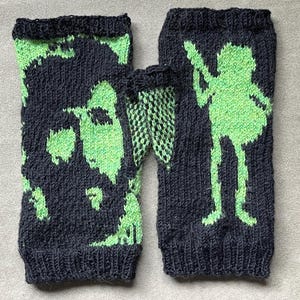 May include: A pair of dark blue knitted arm warmers with a neon green design. One arm warmer features a silhouette of a person playing a stringed instrument. The other arm warmer has a green abstract design.