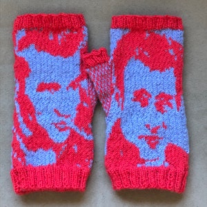 May include: A pair of knitted fingerless gloves with a red and purple color scheme. The gloves feature a knitted image of a person's face.
