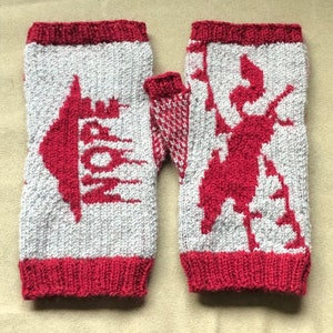 May include: A pair of knitted fingerless gloves with a red and white design. One glove features a stylized deer, while the other has a geometric pattern.