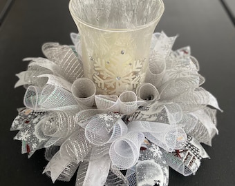 May include: White and silver mesh candle holder with a clear glass votive and a snowflake design. The holder is decorated with white and silver ribbon.
