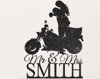 May include: Black glitter cake topper featuring a silhouette of a couple riding a motorcycle with the text "Mr & Mrs SMITH".