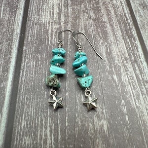 May include: A pair of turquoise and silver dangle earrings with star charms. The earrings feature multiple turquoise stones in various shapes and sizes.