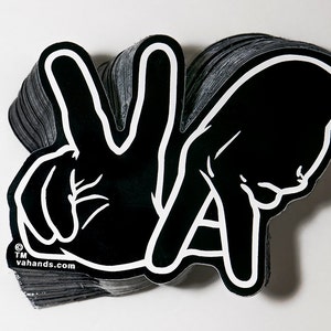 May include: Black and white sticker with the letters "VA" formed by two hands making the peace sign. The sticker has the text "vahands.com" at the bottom.