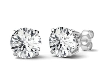 May include: A pair of round-cut diamond stud earrings. The diamonds are set in a silver-coloured metal, with a four-prong setting. The earrings are displayed against a white background.