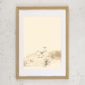 May include: A framed wall art print featuring a minimalist line drawing of a hillside village with a central tower. The artwork is rendered in fine brown ink lines on a cream-colored background, enclosed in a light-toned wooden frame.