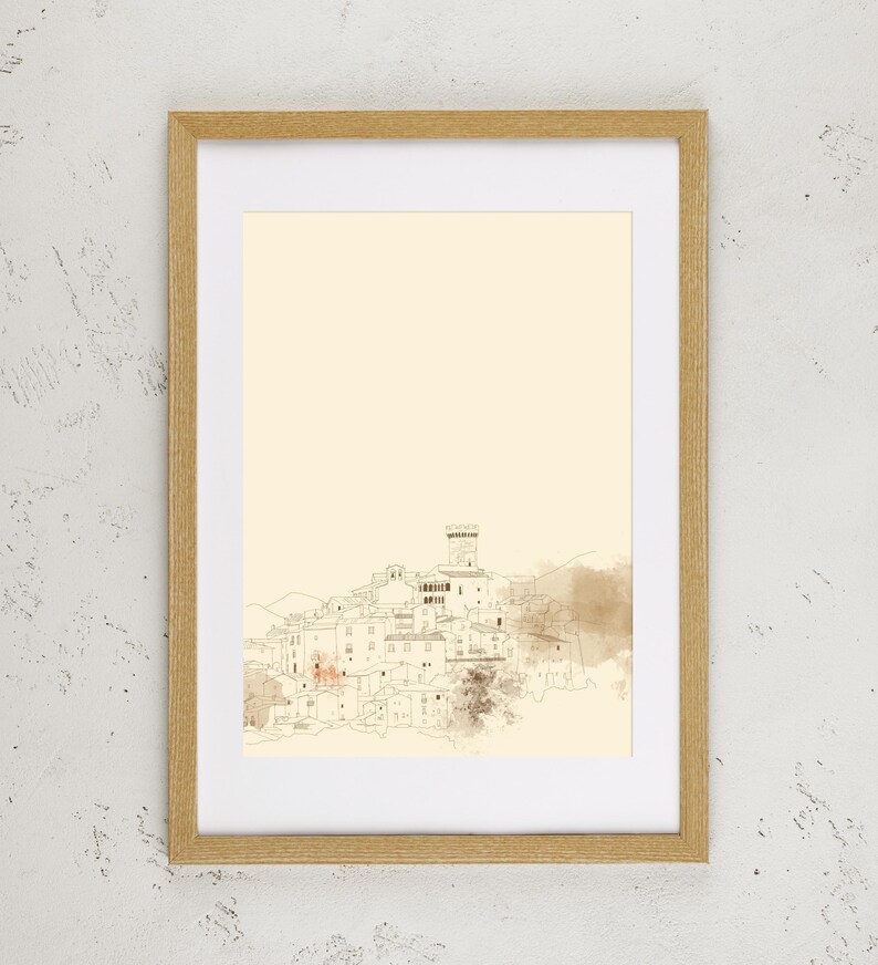 May include: A framed wall art print featuring a minimalist line drawing of a hillside village with a central tower. The artwork is rendered in fine brown ink lines on a cream-colored background, enclosed in a light-toned wooden frame.