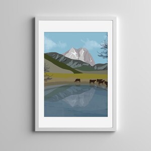 May include: A framed digital art print featuring a mountain landscape with a snow-capped peak, a grassy meadow, and a calm lake reflecting the mountains. A small herd of dark brown cows stands near the water's edge under a light blue sky.